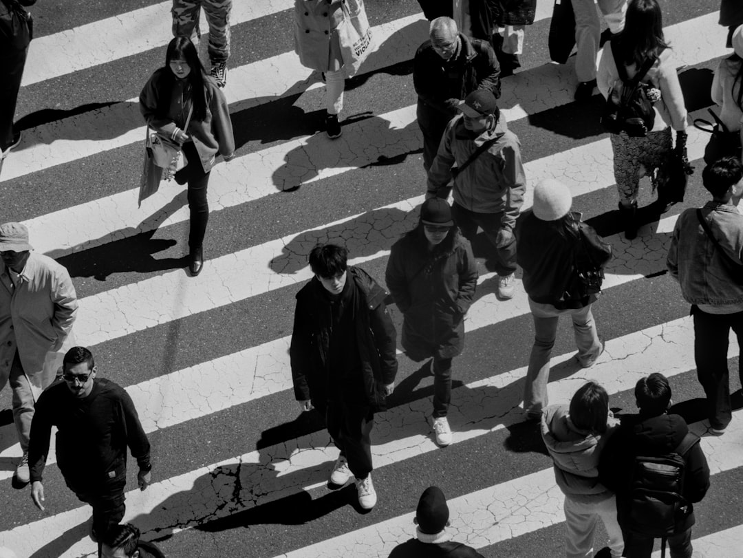 People cross a busy crosswalk in black and white.